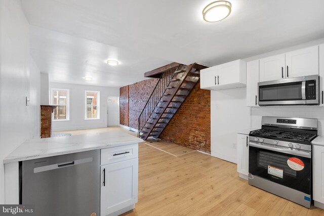 unfurnished living room with light hardwood / wood-style flooring, brick wall, and sink