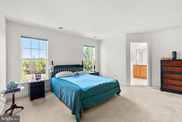 carpeted bedroom featuring ensuite bathroom and multiple windows