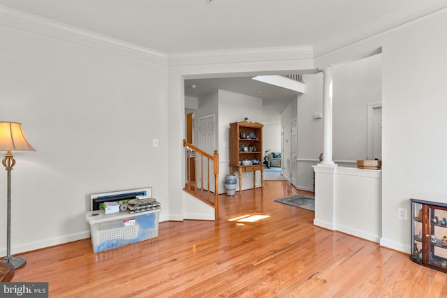 interior space with crown molding, decorative columns, and light hardwood / wood-style floors