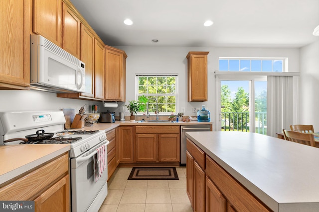 kitchen with light tile patterned floors, white appliances, and sink