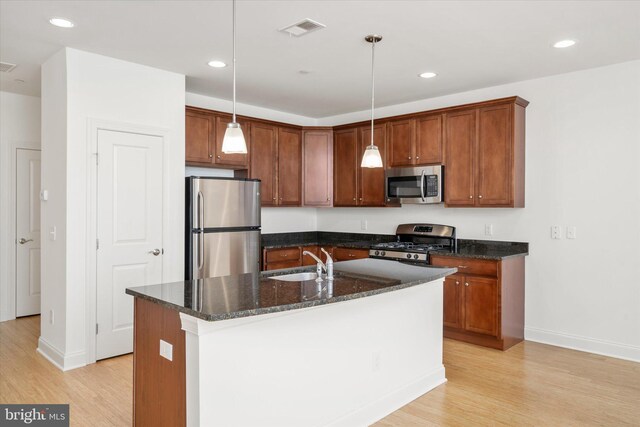 kitchen featuring visible vents, dark stone counters, a sink, stainless steel appliances, and light wood-type flooring