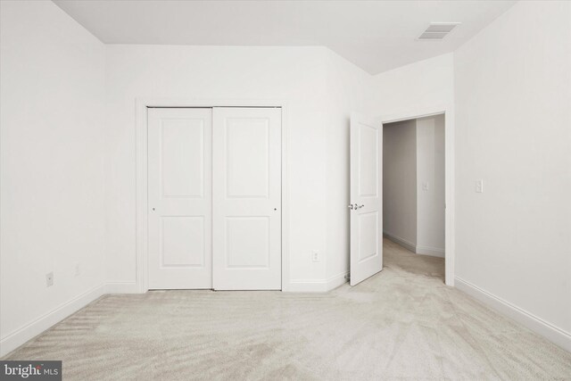 unfurnished bedroom featuring baseboards, visible vents, light carpet, and a closet