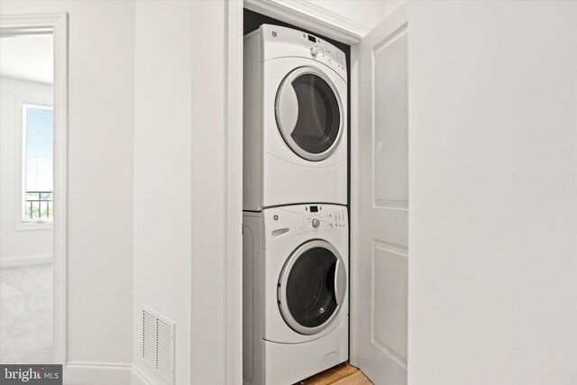 washroom with laundry area, visible vents, and stacked washing maching and dryer