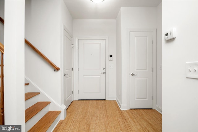 foyer with stairs, light wood-style floors, and baseboards