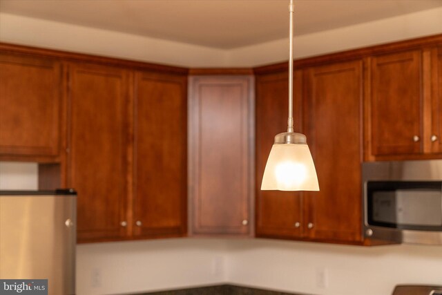 kitchen featuring brown cabinetry, stainless steel microwave, and fridge