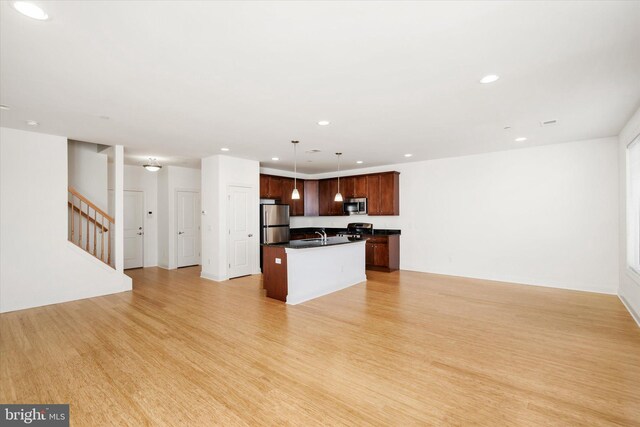 kitchen with dark countertops, light wood-type flooring, open floor plan, and stainless steel appliances