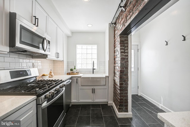 kitchen featuring dark tile patterned floors, tasteful backsplash, sink, white cabinets, and stainless steel appliances