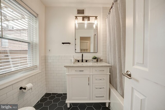 full bathroom featuring tile walls, shower / tub combo, tile patterned floors, vanity, and toilet