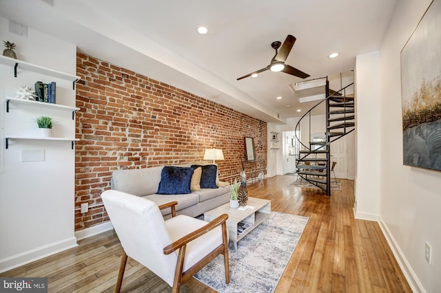 living room featuring ceiling fan, light hardwood / wood-style flooring, and brick wall