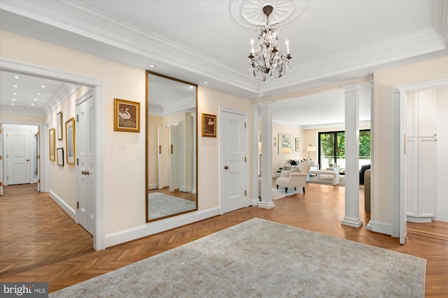 foyer entrance featuring ornamental molding, a chandelier, light parquet flooring, and ornate columns