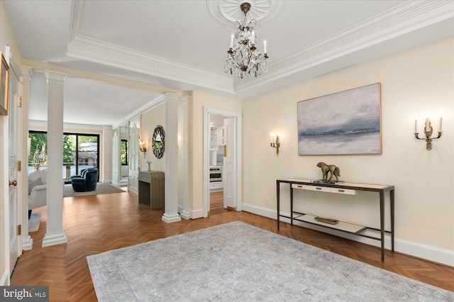 entrance foyer with parquet flooring, a tray ceiling, decorative columns, ornamental molding, and a chandelier