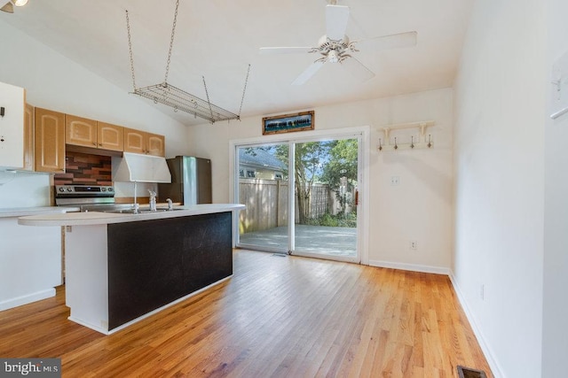 kitchen featuring light hardwood / wood-style floors, an island with sink, stainless steel appliances, ceiling fan, and light brown cabinetry