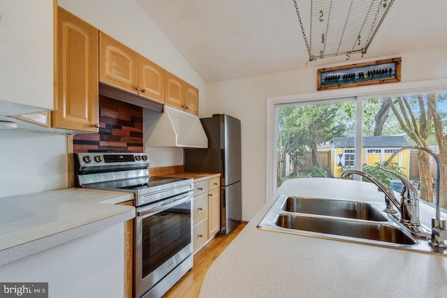 kitchen with sink, stainless steel appliances, light wood-type flooring, vaulted ceiling, and decorative backsplash