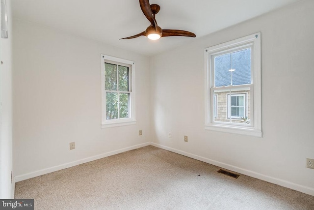 carpeted empty room featuring ceiling fan and plenty of natural light