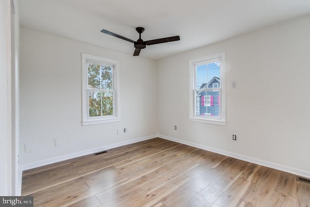 empty room with ceiling fan, plenty of natural light, and light hardwood / wood-style floors