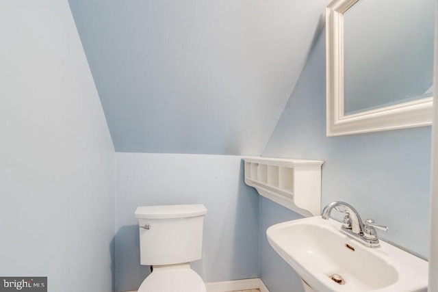 bathroom with vaulted ceiling, sink, and toilet