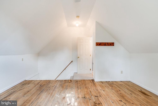 additional living space featuring light wood-type flooring and vaulted ceiling