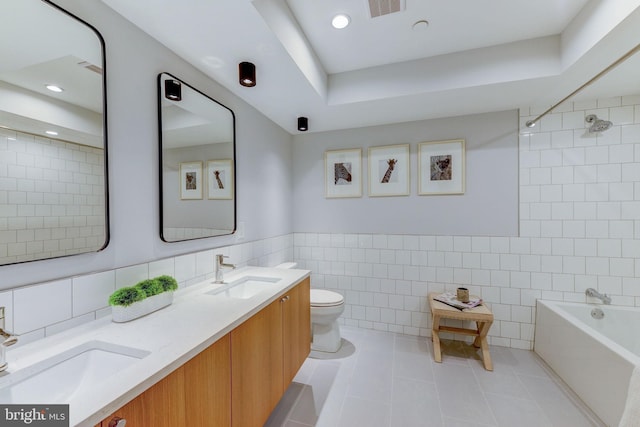 full bathroom with vanity, tile walls, toilet, tile patterned floors, and tiled shower / bath combo