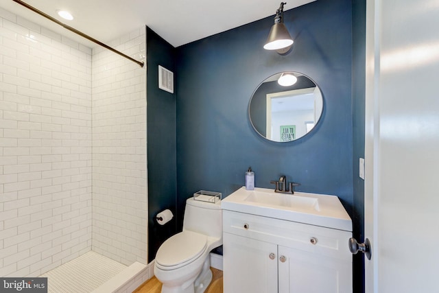 bathroom featuring vanity, toilet, hardwood / wood-style flooring, and a tile shower