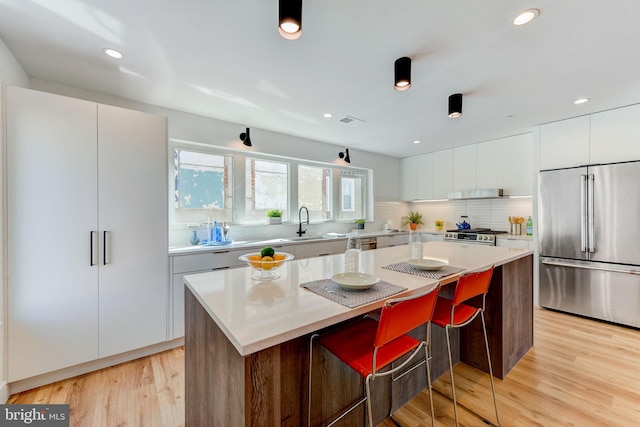 kitchen with a center island, stainless steel appliances, light hardwood / wood-style floors, and a breakfast bar