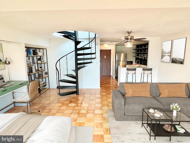 living room featuring a ceiling fan and stairs