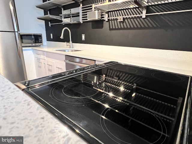 kitchen featuring appliances with stainless steel finishes, sink, and white cabinets