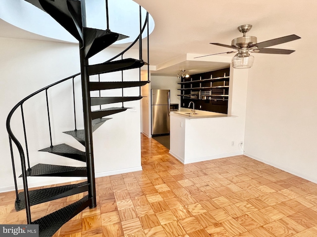 stairway featuring ceiling fan with notable chandelier, parquet flooring, and sink