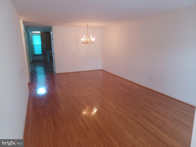 unfurnished room featuring hardwood / wood-style floors and a notable chandelier