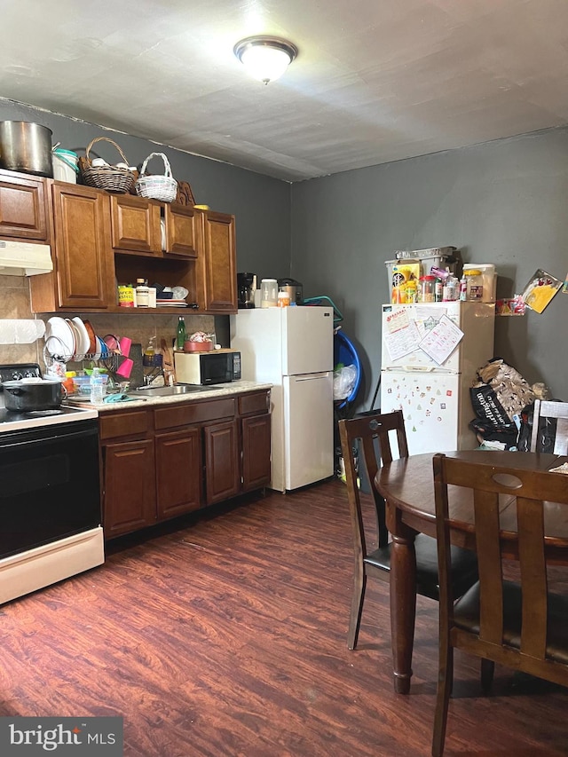 kitchen with white appliances and dark hardwood / wood-style floors