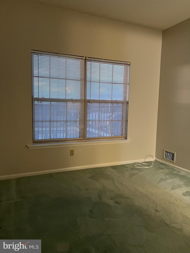 carpeted spare room featuring visible vents and baseboards