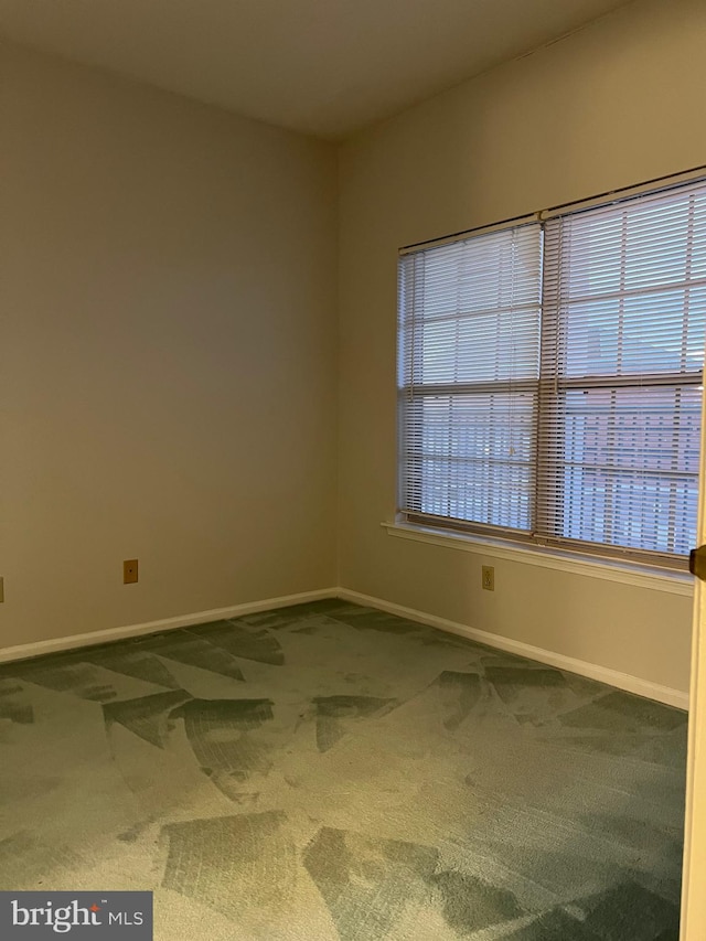 carpeted empty room featuring baseboards