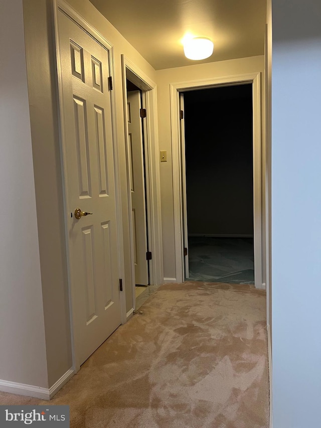 hallway featuring carpet and baseboards