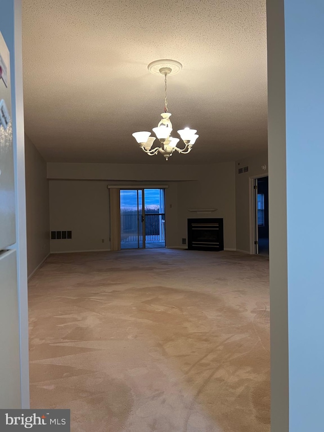 unfurnished living room with visible vents, carpet, a chandelier, and a textured ceiling