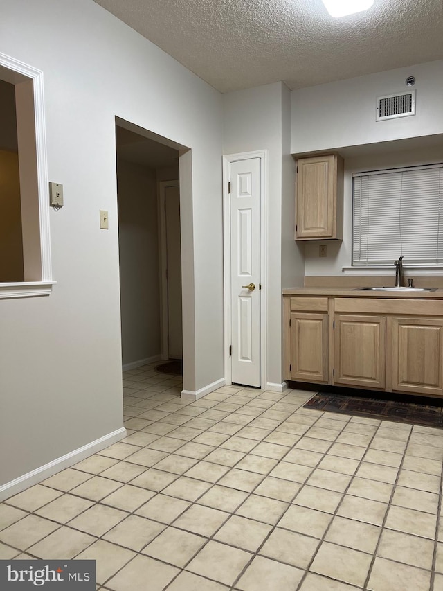 kitchen with visible vents, light brown cabinets, a sink, light countertops, and light tile patterned floors