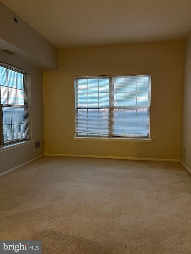 carpeted spare room featuring visible vents and baseboards