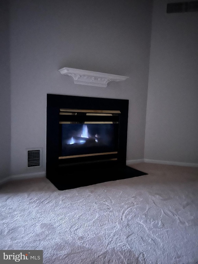 interior details with a fireplace with flush hearth, baseboards, visible vents, and carpet floors