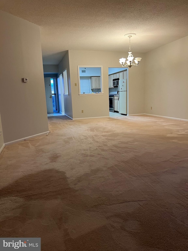 unfurnished room with baseboards, light colored carpet, an inviting chandelier, and a textured ceiling