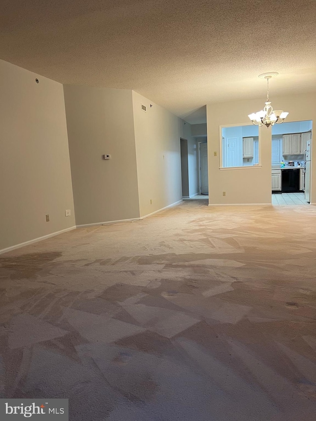 unfurnished living room featuring visible vents, baseboards, light carpet, a notable chandelier, and a textured ceiling