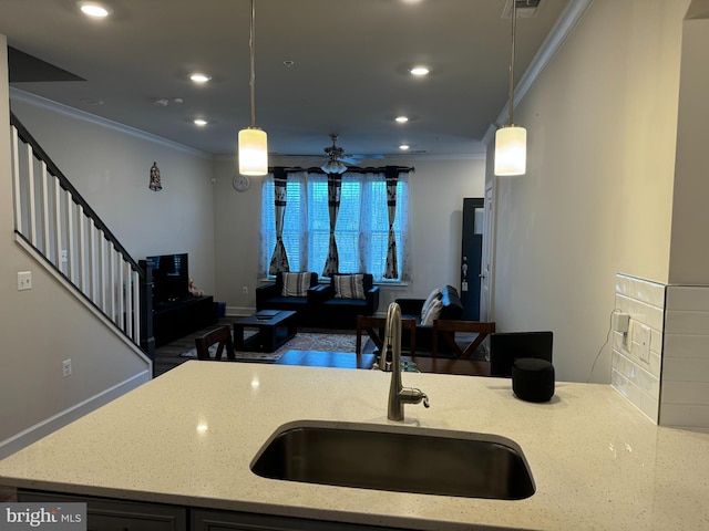 kitchen featuring light stone counters, hanging light fixtures, ceiling fan, and sink