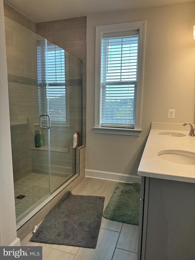 bathroom with hardwood / wood-style floors, vanity, and a shower with shower door