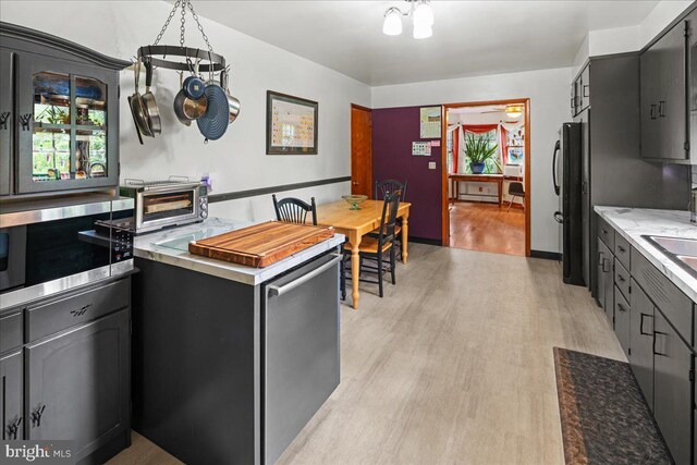 kitchen featuring a notable chandelier, light hardwood / wood-style floors, and black refrigerator