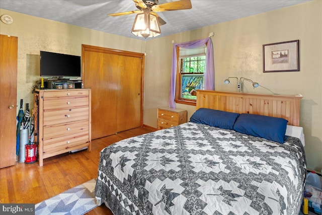 bedroom featuring a textured ceiling, light hardwood / wood-style flooring, ceiling fan, and a closet