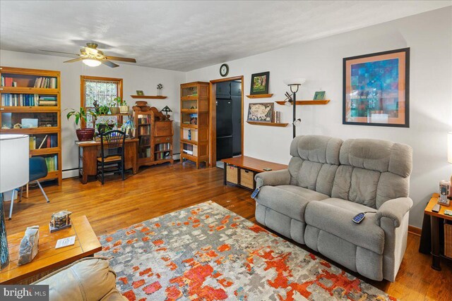 living room with a baseboard heating unit, ceiling fan, and hardwood / wood-style flooring