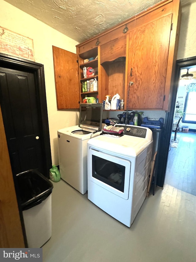 laundry room featuring a textured ceiling, cabinets, and independent washer and dryer