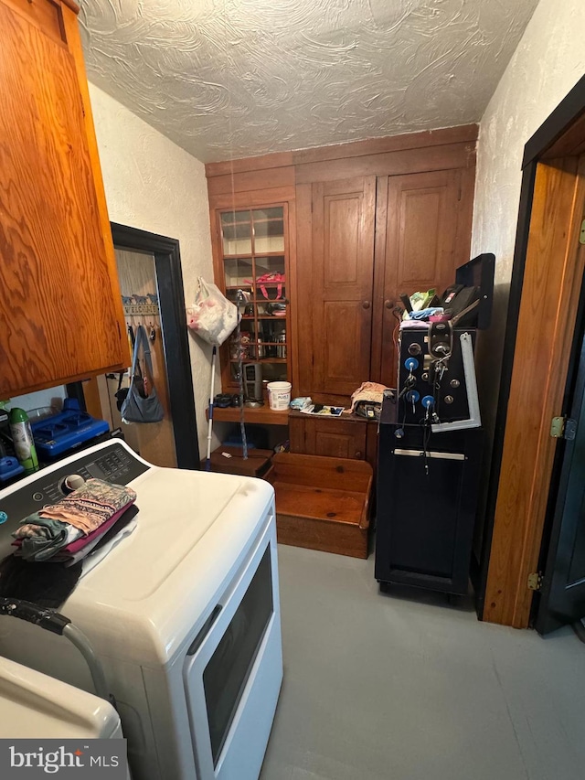 bedroom with washer / dryer, concrete floors, and a textured ceiling