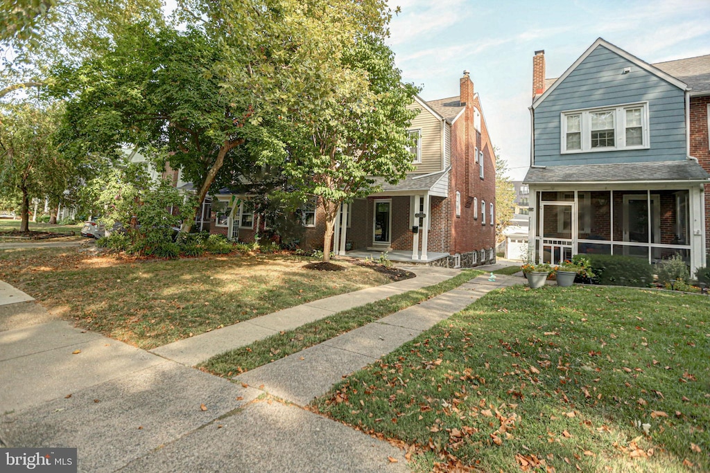 view of front of home featuring a sunroom and a front lawn