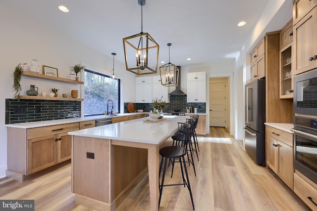 kitchen featuring a center island, stainless steel appliances, a kitchen breakfast bar, decorative backsplash, and light wood-type flooring