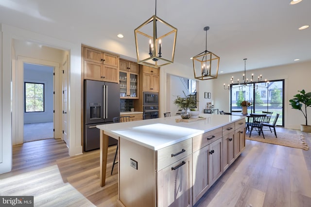 kitchen with a breakfast bar, high end refrigerator, oven, a large island, and a notable chandelier