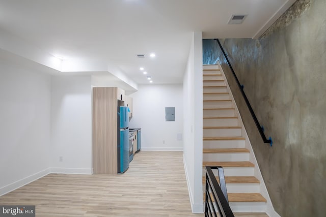 stairway with electric panel, visible vents, baseboards, and wood finished floors