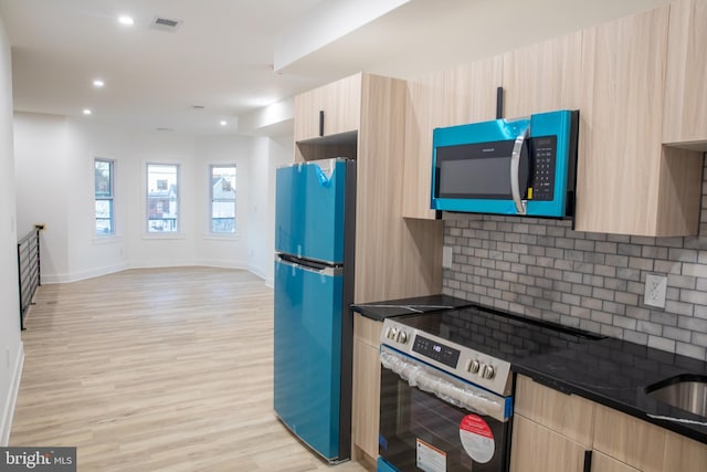 kitchen with stainless steel electric range oven, modern cabinets, light brown cabinetry, and freestanding refrigerator